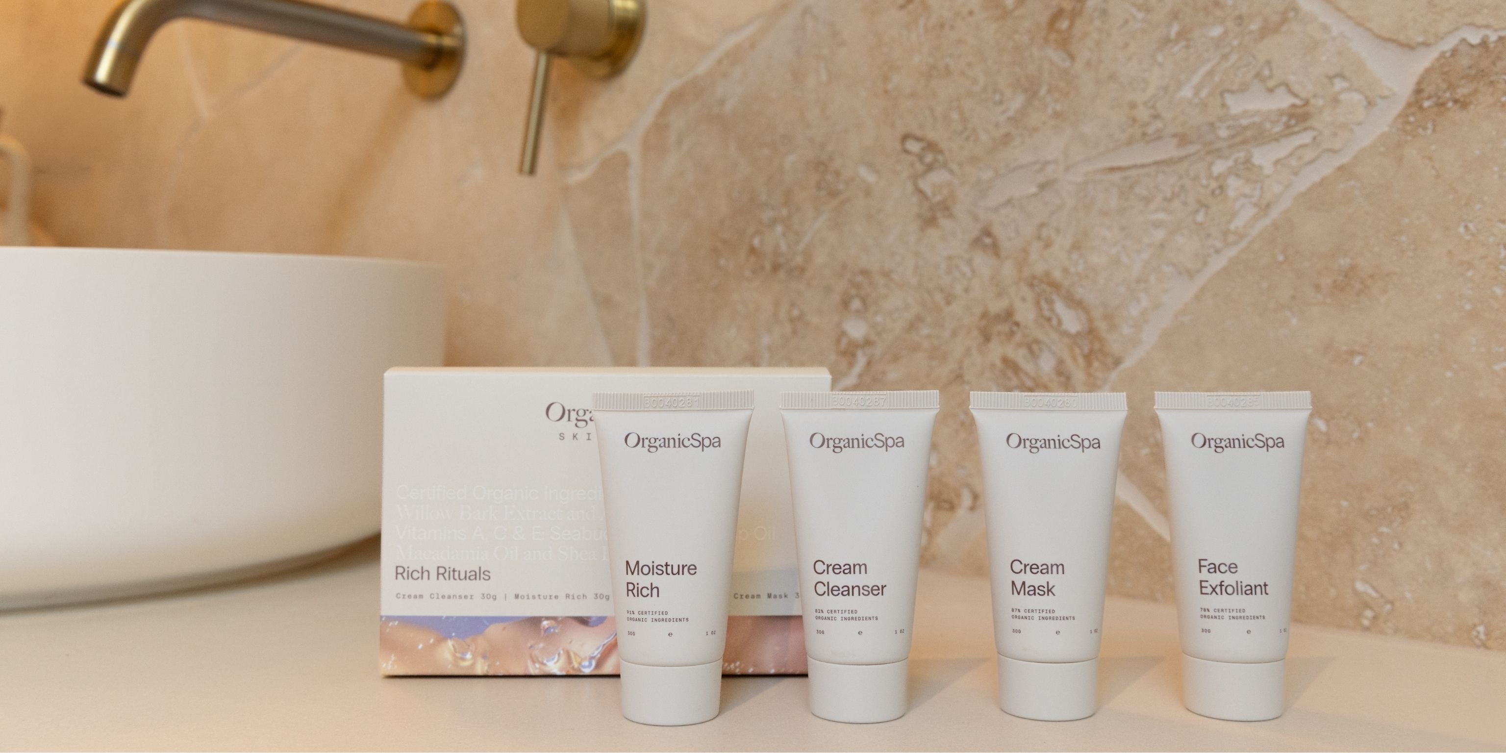 OrganicSpa Rich Rituals mini set displayed in a bathroom — Moisture Rich, Cream Cleanser, Cream Mask and Face Exfoliant, Certified Organic skincare for mature complexions.