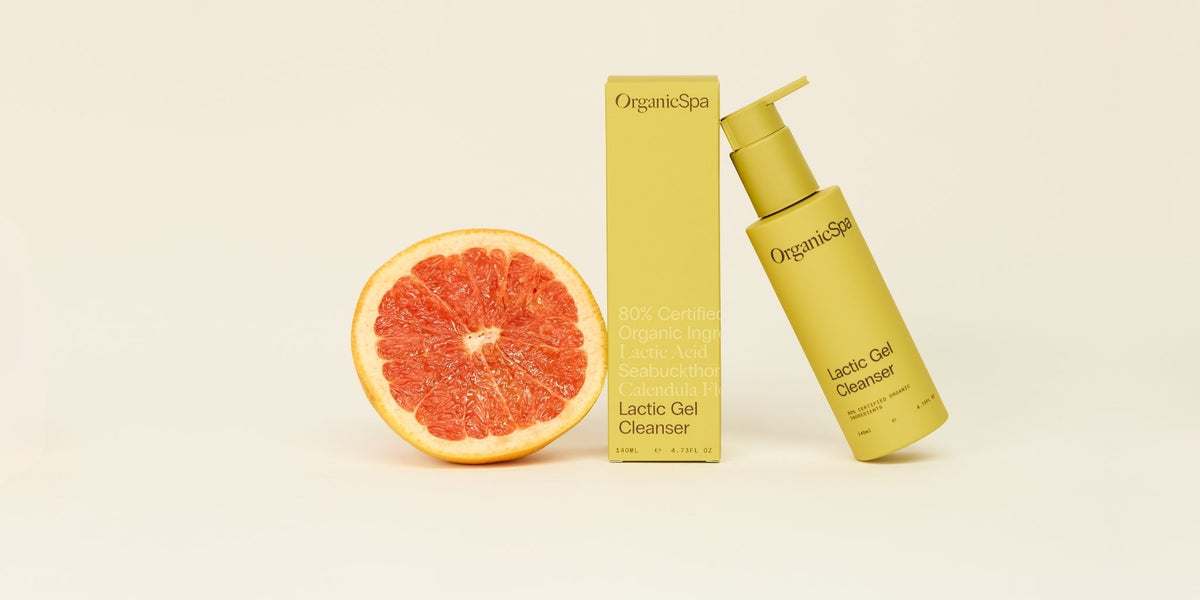 OrganicSpa Lactic Gel Cleanser, a chartreuse 140ml pump bottle leaning against its matching carton, with a halved pink grapefruit beside them. The carton reads 80% Certified Organic Ingredients, Lactic Acid, Seabuckthorn, Calendula Flower.