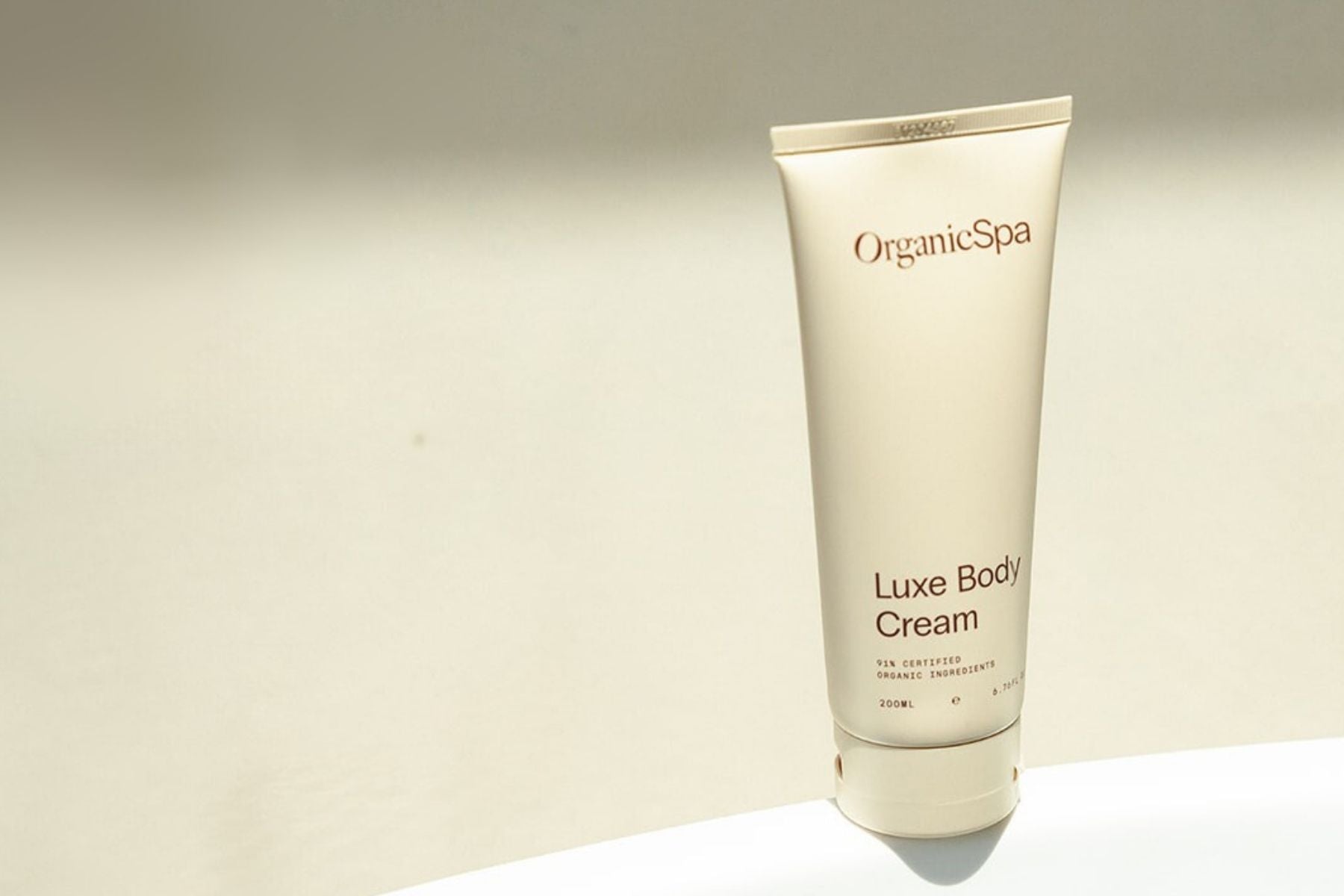 Organic Spa Luxe Body Cream tube on a neutral background.
