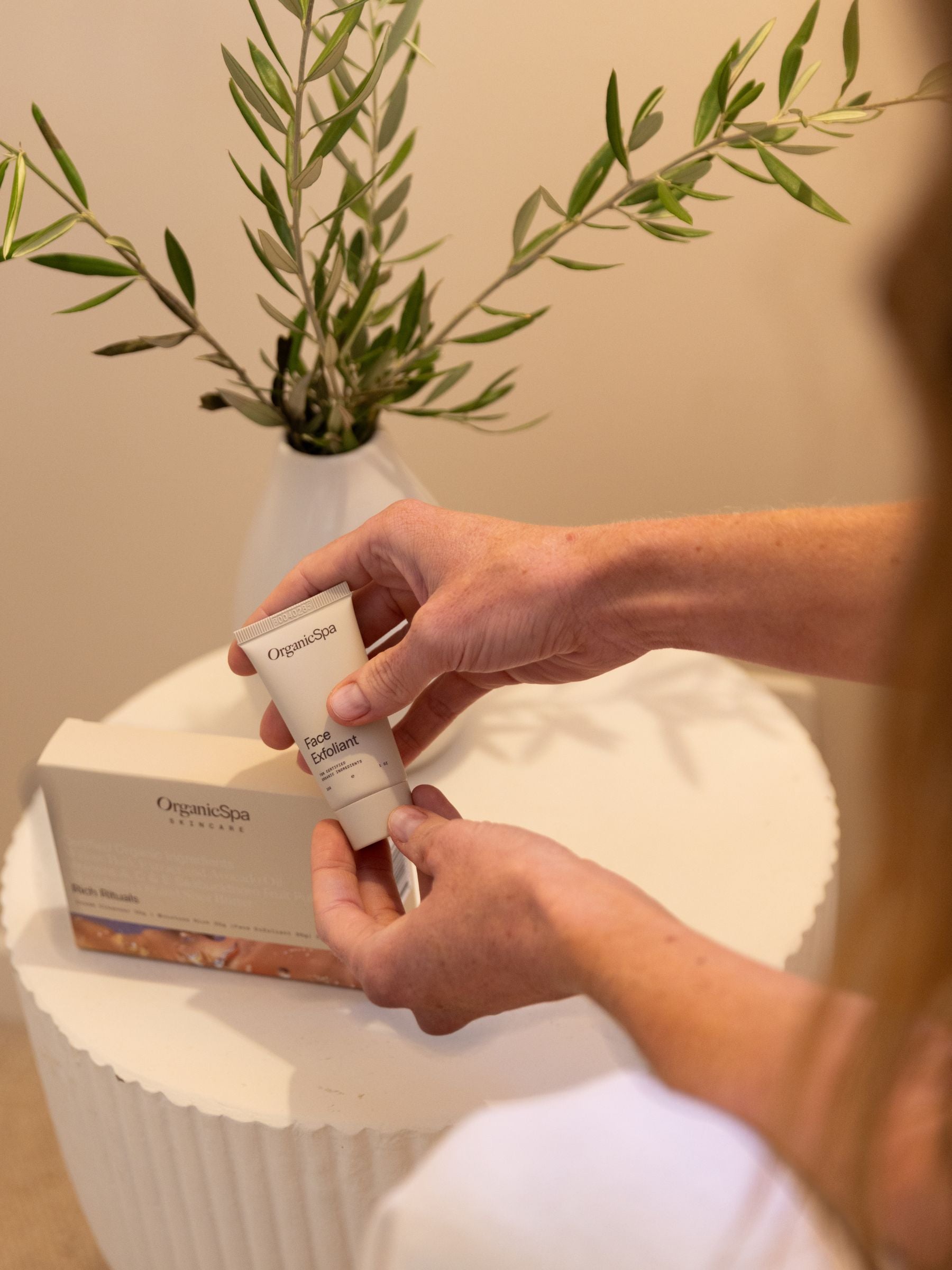 Hand holding OrganicSpa Face Exfoliant from the Rich Rituals set, a Certified Organic skincare collection for drier, mature complexions.