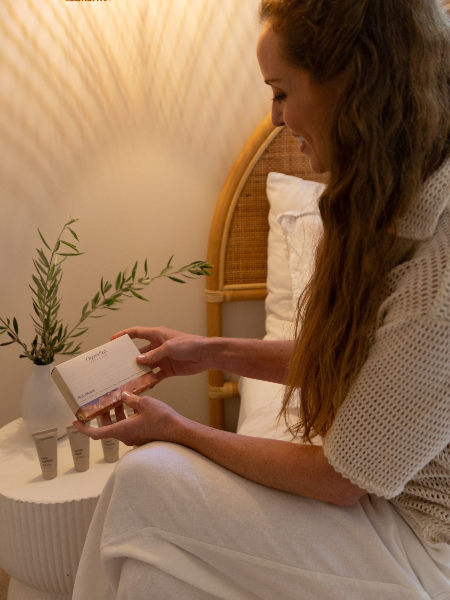 Woman smiling while holding the OrganicSpa Rich Rituals box, a Certified Organic mini skincare set for nourishing drier, mature skin.