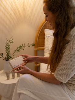 Woman smiling while holding the OrganicSpa Rich Rituals box, a Certified Organic mini skincare set for nourishing drier, mature skin.