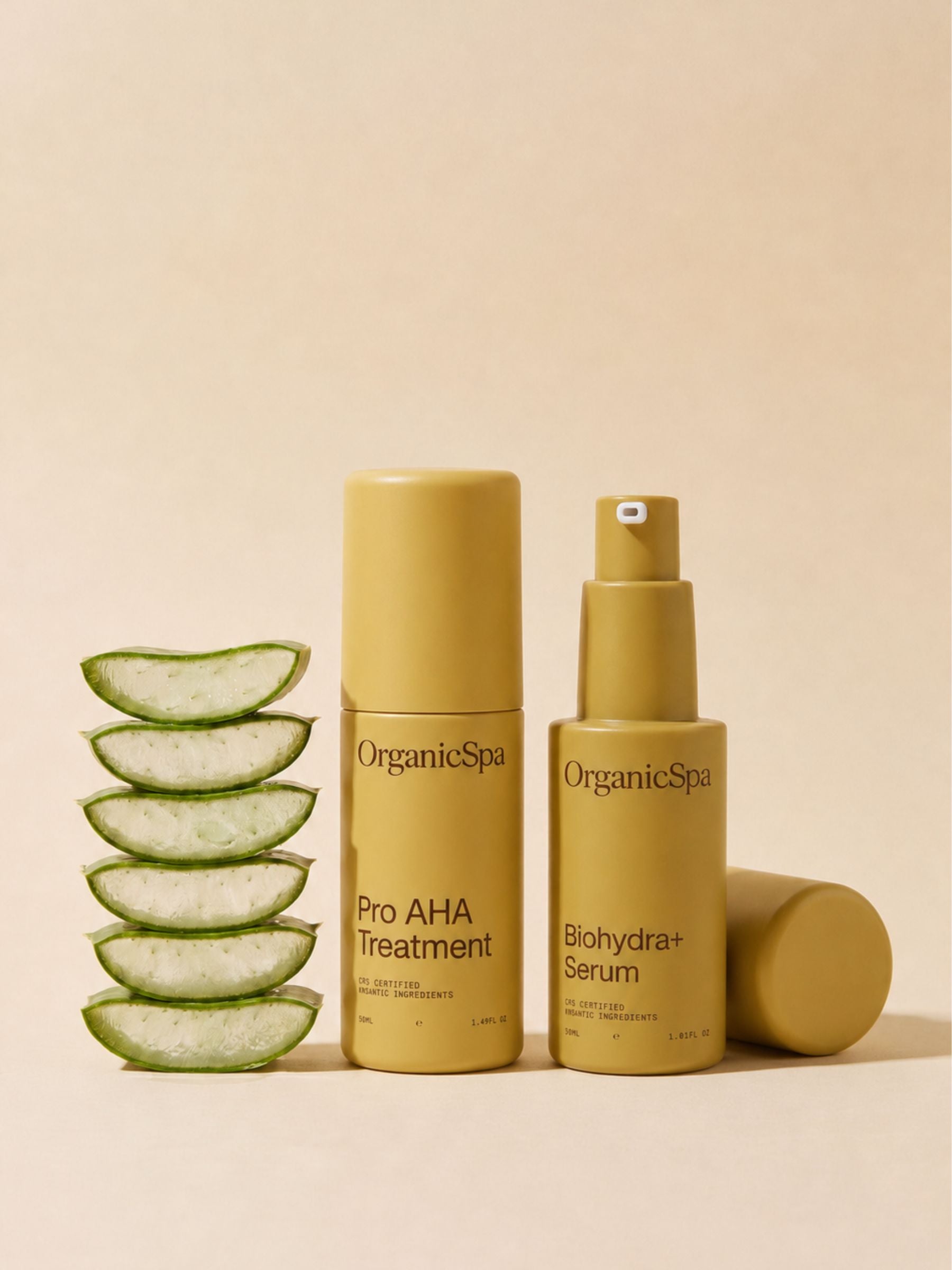 OrganicSpa Hydra-Renewal Active Duo — Pro AHA Treatment and Biohydra+ Serum in olive bottles beside a stack of fresh aloe vera slices on a soft beige background.