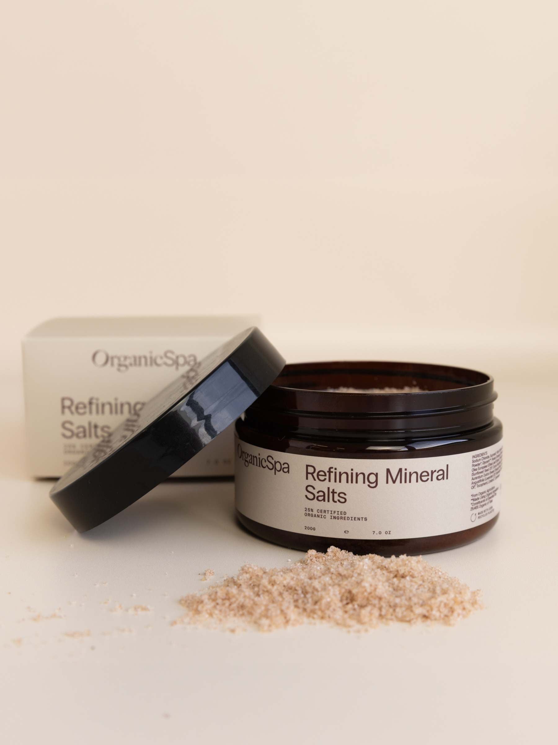 OrganicSpa Refining Mineral Salts 200g — Certified Organic body scrub in an amber glass jar, shown beside its outer carton with a scatter of product.