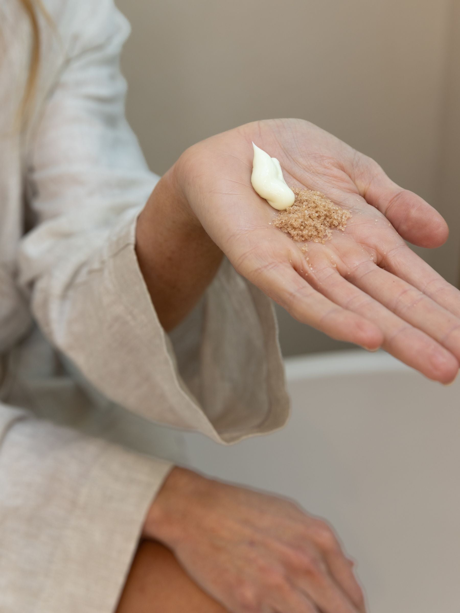 Close-up of an open palm holding a dollop of white body cream alongside a small amount of mineral salt granules, showing the texture of both products in the OrganicSpa Body Ritual Set