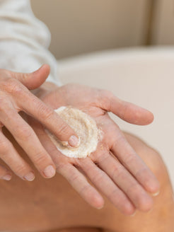 Close-up of two hands blending mineral salt and body cream together in the palm, showing the combined texture of the OrganicSpa Body Ritual Set