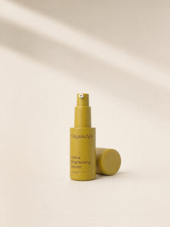 OrganicSpa Active Brightening Serum, a chartreuse 30ml bottle marked 85% Certified Organic Ingredients, with its cap lying beside it.