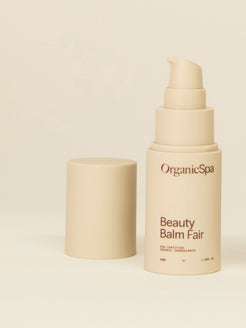 Organicspa Beauty Balm Fair bottle with pump and lid displayed on a soft beige background.
