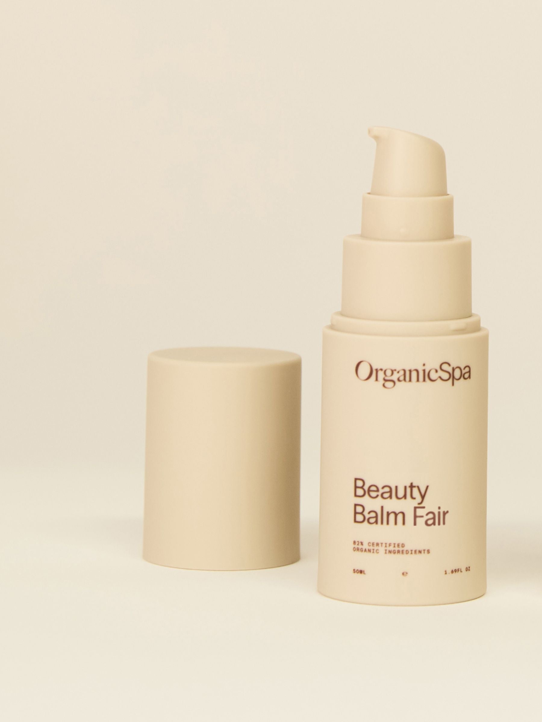 Organicspa Beauty Balm Fair bottle with pump and lid displayed on a soft beige background.