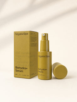 OrganicSpa Biohydra+ Serum, a chartreuse 30ml pump bottle with its cap lying beside it, standing next to its matching carton. The carton reads 93% Certified Organic Ingredients, PGA, Hyaluronic Acid, Calendula Extract, Organicsceuticals Skincare, made with recyclable glass, and Formulated with purpose, just like in nature.