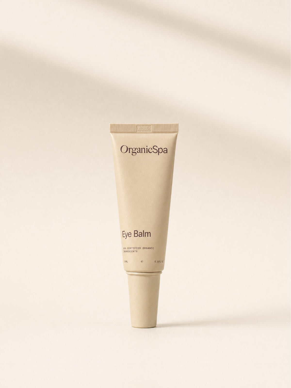 OrganicSpa Eye Balm, a sand-coloured 15ml tube marked 89% Certified Organic Ingredients, in soft light.