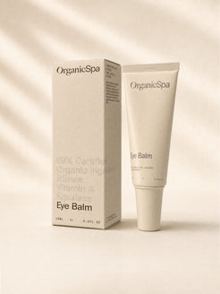 OrganicSpa Eye Balm, a sand-coloured 15ml tube standing beside its matching carton. The carton reads 89% Certified Organic Ingredients, Ribose, Vitamin A, Squalane, and made with 50% recycled plastic.