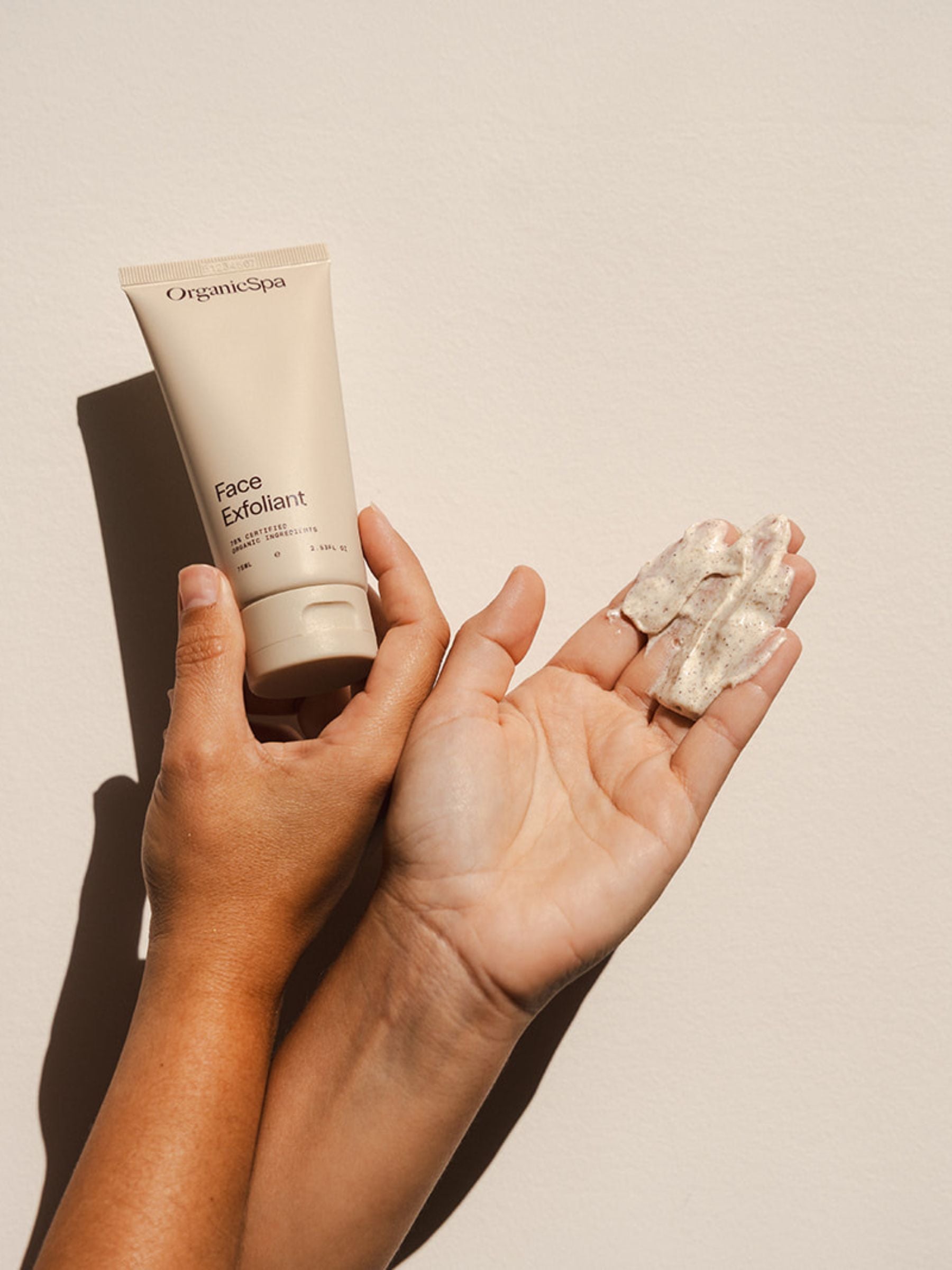 Hands holding Organicspa Face Exfoliant and its creamy scrub texture, certified organic facial exfoliant made in Australia.