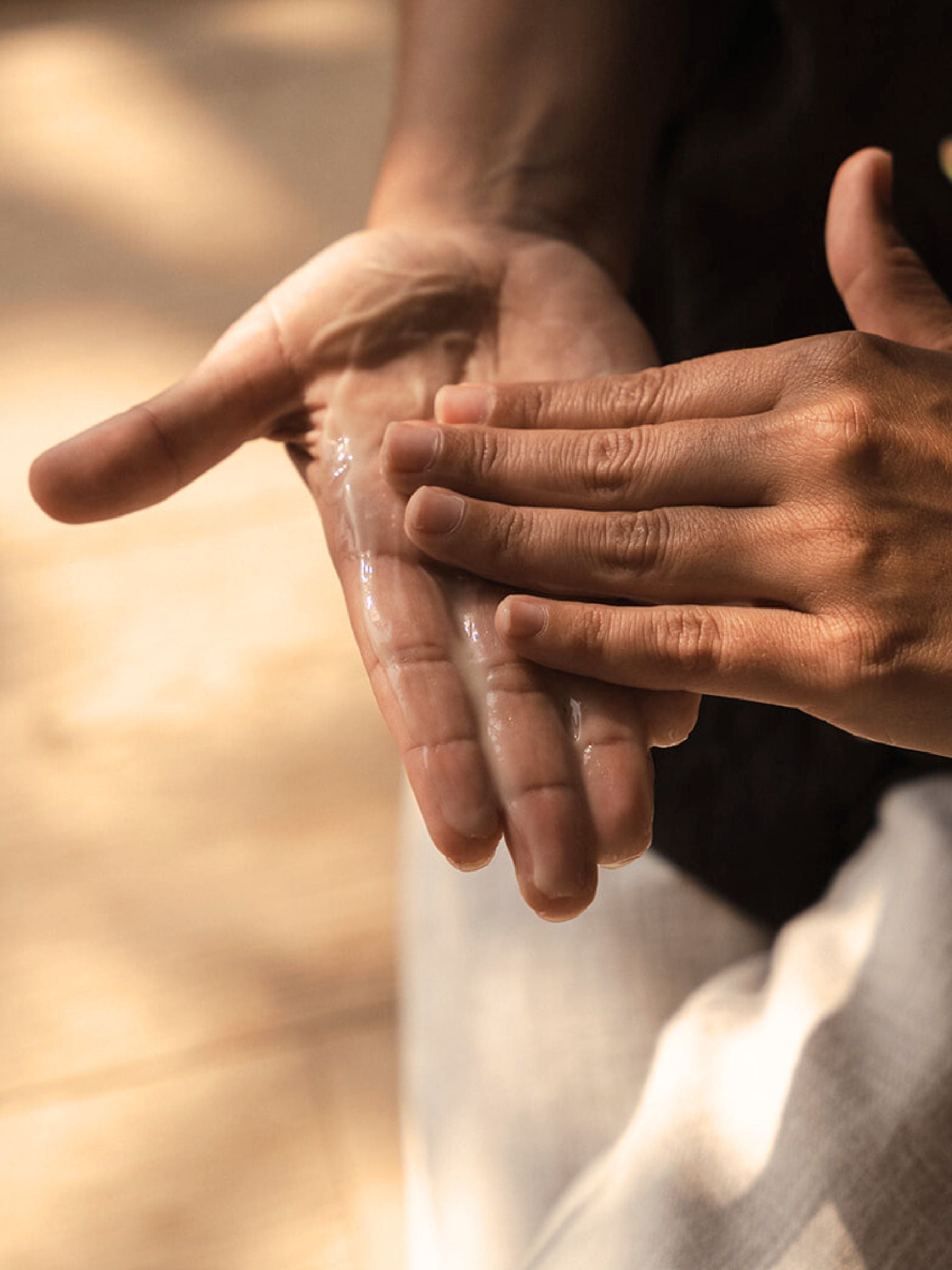 Close-up of hands rubbing together a clear layer of Organicspa Gel Mask, revealing its lightweight gel texture.