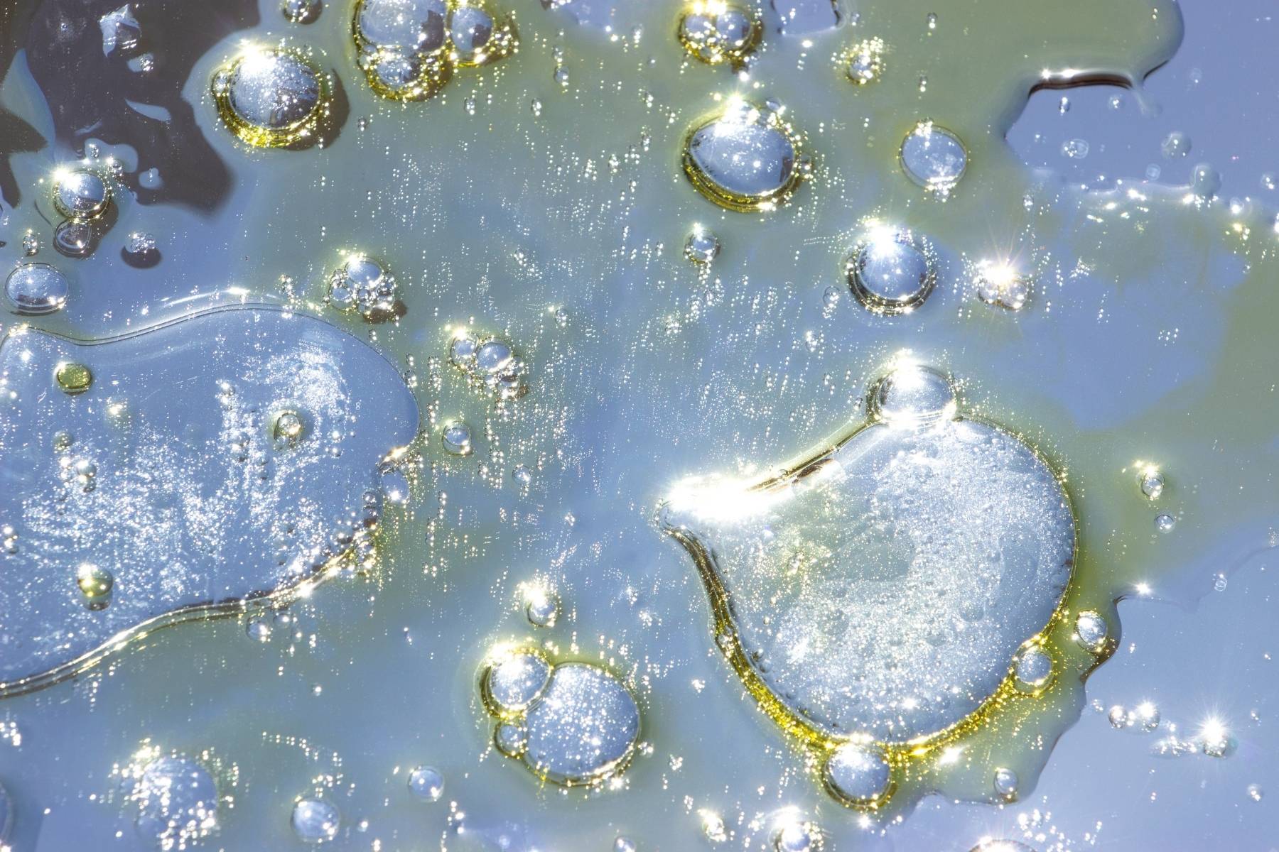 Shimmering droplets of Australian macadamia nut oil and lavender essence floating in a clear liquid, reflecting the pure and sustainable oils used in our organic spa treatments.