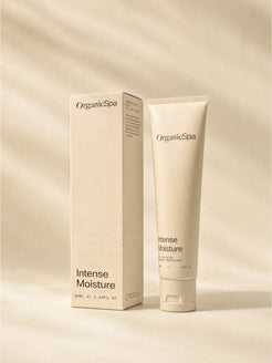 OrganicSpa Intense Moisture, a sand-coloured 50ml tube standing beside its matching carton. The carton reads 87% Certified Organic Ingredients, Cocoa Seed Butter, Carrot Seed Oil, Hyaluronic Acid, and made with 50% recycled plastic.