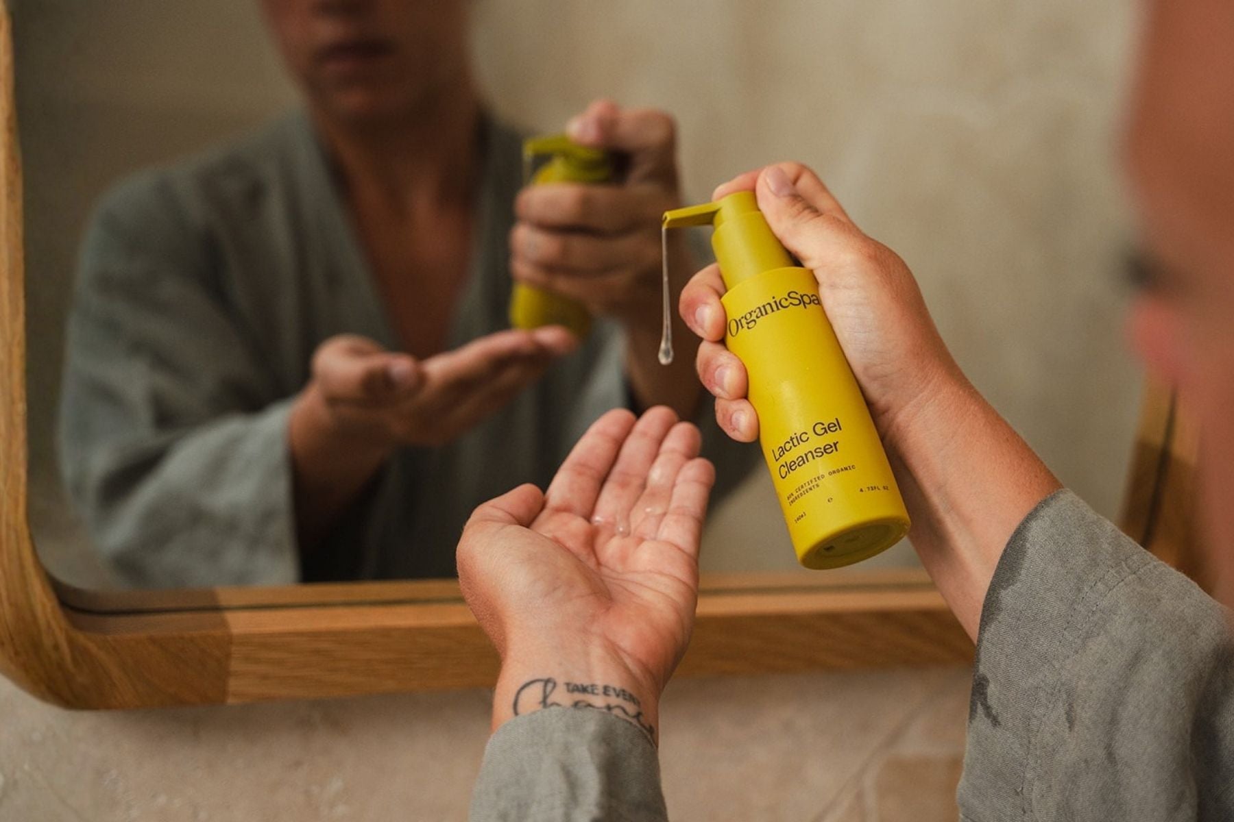 A person dispensing a pump of OrganicSpa Lactic Gel Cleanser in a modern bathroom, highlighting our vegan and cruelty-free professional-grade formula made in Australia.