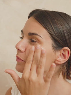 A woman gently presses Organicsceuticals Biohydra+ Serum into the skin around her eye and cheek in a soft side profile, before the video moves into a close-up of the serum absorbing into the skin, visibly dewy. Warm neutral background, slow and unhurried movement. Certified Organic Skincare.


